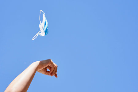 someone flying a kite in the air with their hand and fingers extended to one another persons arm, against a blue sky backgroundの写真素材