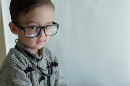 a little boy with glasses and a stel on his head, looking at the camera while he is wearing a stelの写真素材
