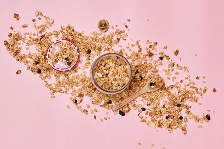 granos on a pink background with spoons and bowls full of granos scattered in the top right cornerの写真素材