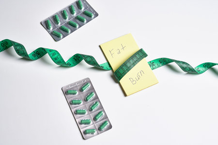 some pills and tape on a white surface with the words bm written in green letters next to each pillの写真素材