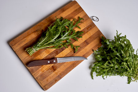 some greens on a cutting board next to a knife and a piece of lete with its end cut in halfの写真素材