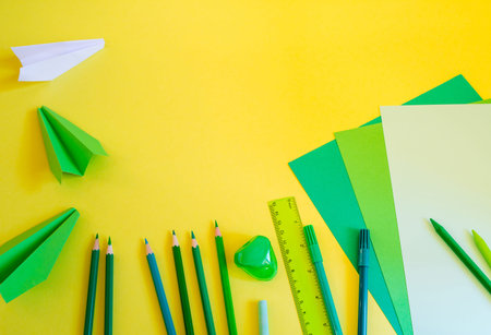 Creative, fashionable, minimalistic, school or office workspace with green supplies on yellow...