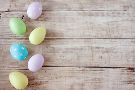 Easter eggs painted in pastel colors on wooden background. Pastel, hand painted Easter eggs. Top...