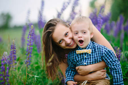 Beautiful woman and her cute little son are smiling, on lupine fieldの写真素材