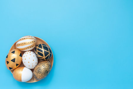 Top view of easter eggs colored with golden and black paint in differen patterns. Minimal easter concept. Flat Lay of Golden Easter Eggs. Copy space.の写真素材