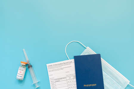 Doctor is holding a vaccination record card and corona virus vaccine vials. Passport of immunity to the coronavirus in the hands of a male doctor. Health passport as proof of recovery from COVID-19.の写真素材