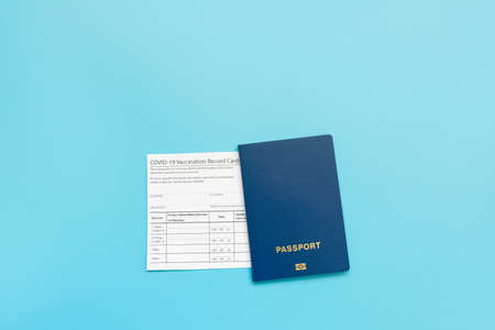 Vaccination record card, passport, a vial with  vaccine. syringe and mask on a blue background, close up, copy space. Immunity passport, risk-free concept.の写真素材