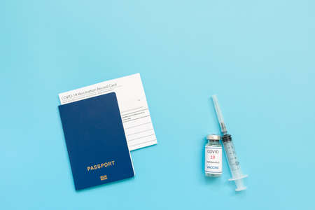 Vaccination record card, passport, a vial with vaccine. syringe and mask on a blue background, close up, copy space. Immunity passport, risk-free concept.の写真素材
