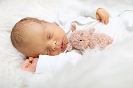Adorable newborn one week age in white bedroom. Newborn child relaxing in bed. Nursery for young children. Textile and bedding for kids. Family morning at home. Lifestyle concept, real life.の写真素材