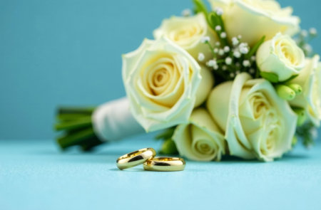 large wedding bouquet of white roses and two gold wedding rings on blue background, wedding card or invitation, wedding booklet or flyerの素材
