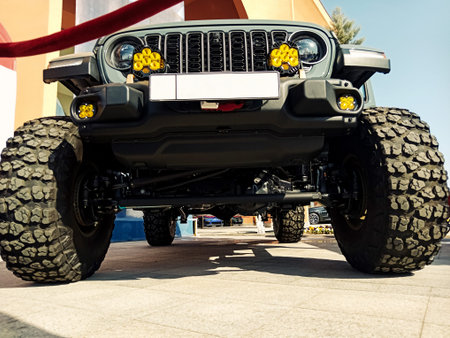 an extreme low-angle shot of the front of a highly lifted suv, showcasing its huge mud tires with...
