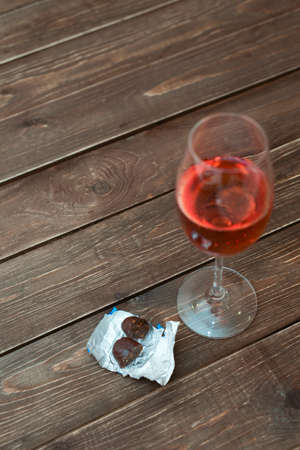 a glass of sparkling rose red wine with chocolate candy on a wooden dark backgroundの写真素材