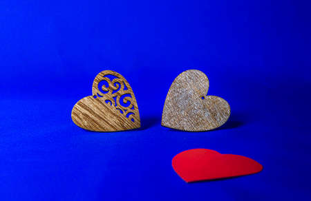 two hearts made of wood and one red heart on a blue backgroundの写真素材