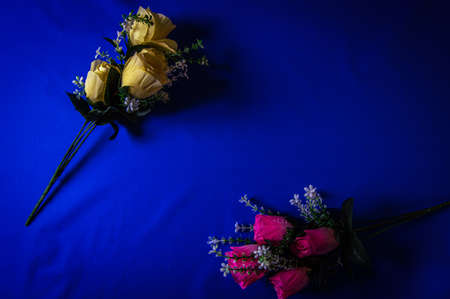 bouquets of artificial pink and yellow flowers on a blue backgroundの写真素材