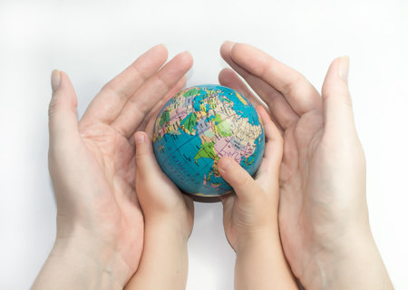 Hands of mother and child holding a globeの写真素材