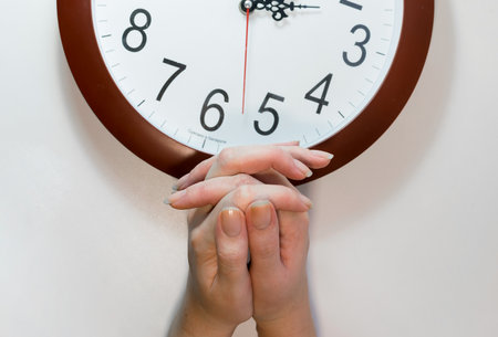 The man folded his hands and placed them in front of the clock faceの写真素材