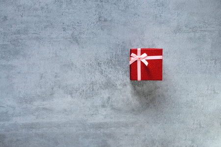 Love gift. Valentine day greeting. Red present box on gray copy space. Advertising background.