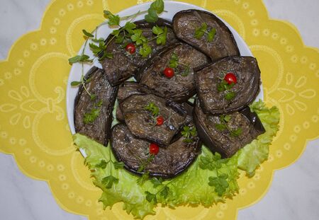 Fried eggplant slices with garlic and cherry tomatoes on a plateの写真素材