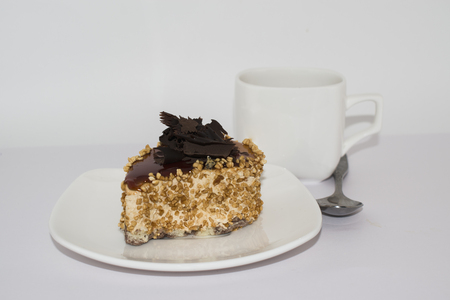 A cake with chocolate on a white plate with white tea Cupの写真素材
