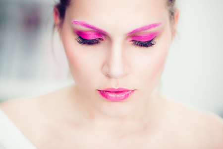 The woman with a bright pink make-up, pink eyebrows and false eyelashes. Studio portrait.の写真素材
