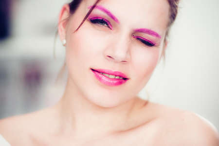 The woman with a bright pink make-up winks. Studio portrait.の写真素材