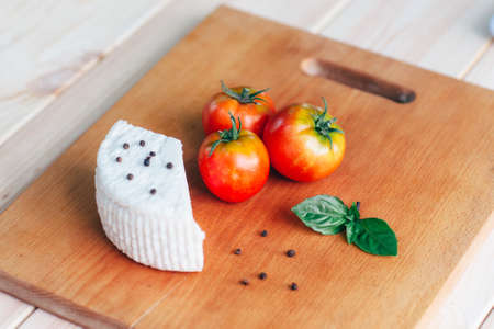 tomatoes,  pepper,basil and homemade cheese on light rustic wooden board, top view. Culinary backgroundの写真素材