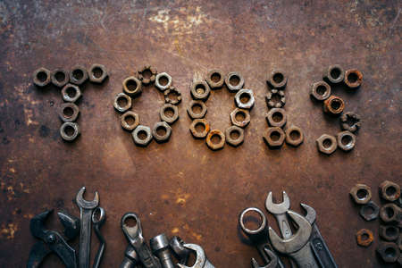 the word Tools written by nuts and a set of wrenches on a rusty metal dark backgroundの写真素材