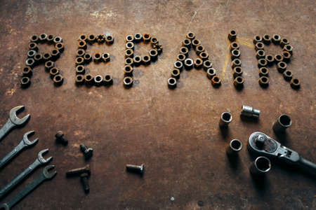 the word Repair made of old nuts. A conceptual photo on a rusty metal background. It is a lot of garage tool which was in the useの写真素材