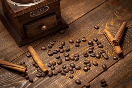 antique coffee mill and beans of coffee with cinnamon sticks on a dark wooden backgroundの写真素材
