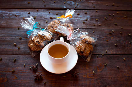 cup of herbal tea, the Indian spices and gift packings of homemade Christmas  cookies with dried fruits and nuts. Healthy food. Dark wooden backgroundの写真素材