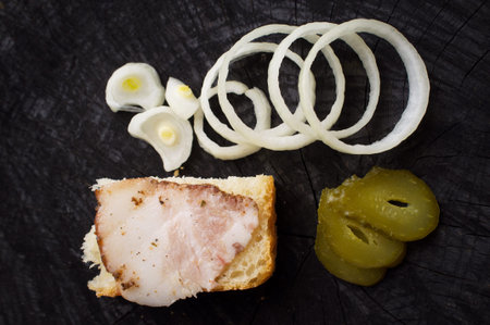 sandwich with becon, , onions and pickled cucumber on a dark kitchen tableの写真素材