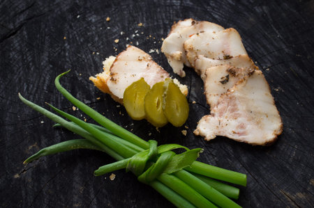 Appetizing slices of becon, green onions and sandwich lie on a dark kitchen tableの写真素材