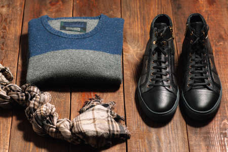 Collection of men's warm autumn clothes on a dark wooden background. scarf,  shoes, sweaters. Goods for internet shop.の写真素材