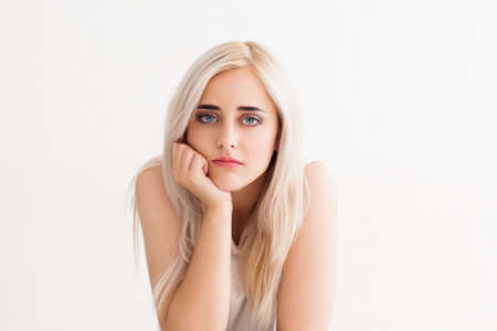 sad beautiful young blond woman bored. Studio photo on a white background with a free field.の写真素材