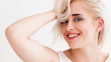 confident blonde with big blue eyes, bright eyebrows. She's flirting, laughing, fooling around with her hair, have fun and looking at the camera. studio photo on white background.の写真素材