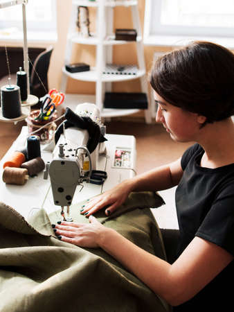 seamstress making clothes. Workplace tailor - sewing machine, rolls of  thread, fabric, scissors.の写真素材