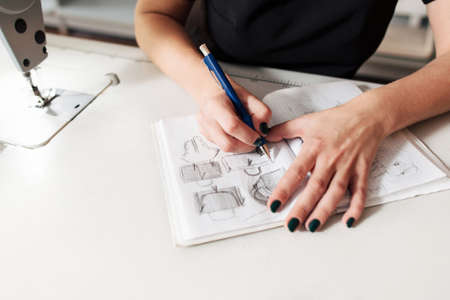 Seamstress creates a sketch in the working notebook. designer draws the clothes and bags.の写真素材