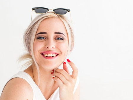 Young fashionable  blonde woman in sunglasses laughing frankly, looking at the camera