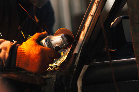 Mechanic doing a metal work, repair automobile with electric grinder. Concept of renovation of old car and garage serviceの写真素材