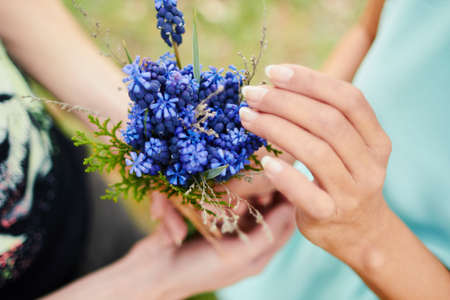 Lovers hands holding a purple bouquet of flowers. Gift of love.の写真素材