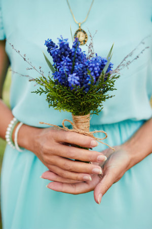 Womens hands holding a purple bouquet of flowers. Gift of love.の写真素材