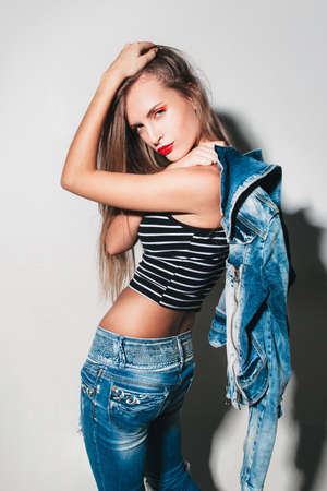 Girl on a white background in a new collection of denim. fashionista in jeans with bright makeupの写真素材