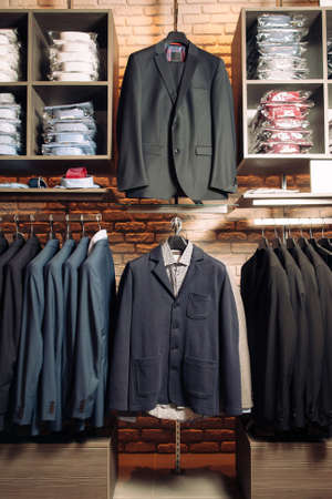 Many men's business suits  and shirts of different colors. Modern boutique with clothes for business people. Vertical photoの写真素材