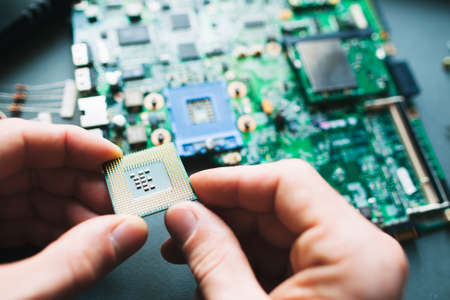 Technician analysis and plug in CPU microprocessor to motherboard socket. Workshop backgroundの写真素材