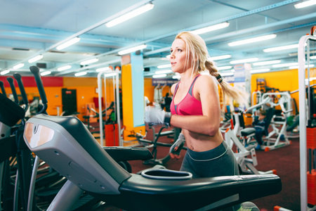 Girl runs on treadmil. Active girl in gym runs on treadmil. Athlete cardio activity on treadmil.