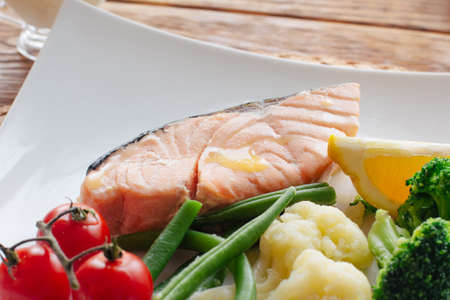 Seafood with boiled assorted vegetables. Salmon steak and steamed vegetables, served on a wite plate. Lenten  healthy food. Top view on dietary seafood, salmon and vegetables side dish.の写真素材