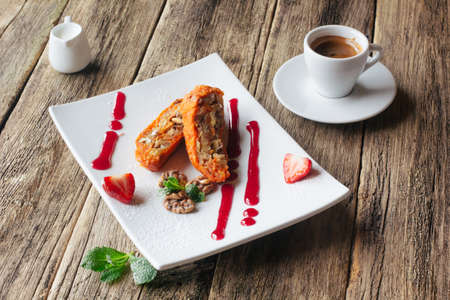 Vegetarian dessert. Carrot apple  sweet roll  with a strawberry sauce and a cup of expresso coffee served on wooden background. Lenten vegeterian desert from fruits.の写真素材