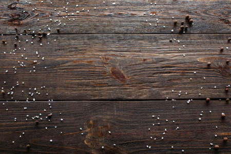 Void wooden background of cutting board with wooden texture and scattered spices on it. Top view on void wooden background with pepper and salt.の写真素材