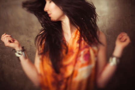 Indian woman with long hair in motion against stone background. Activity of indian woman with flying long hair. Defocused foto of dancing indian girl with blowing hair.の写真素材