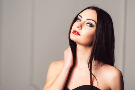 Sensual brunette with bright and bold make-up posing against grey background. Sensual brunette with...